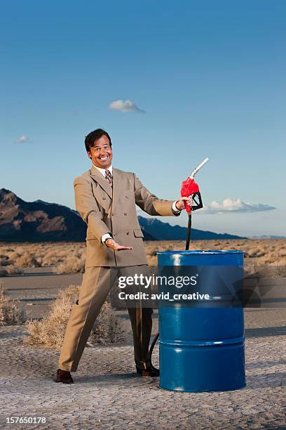 oil executive with barrel of gas in the desert - benzinekan stockfoto's en -beelden