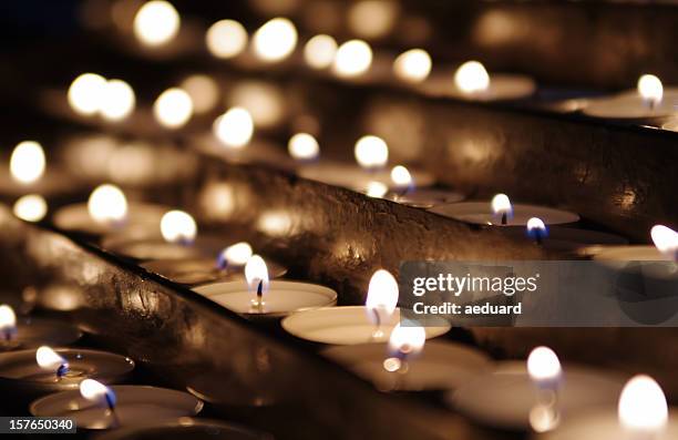 rows of lit tea candles in sepia tones - death photos stockfoto's en -beelden