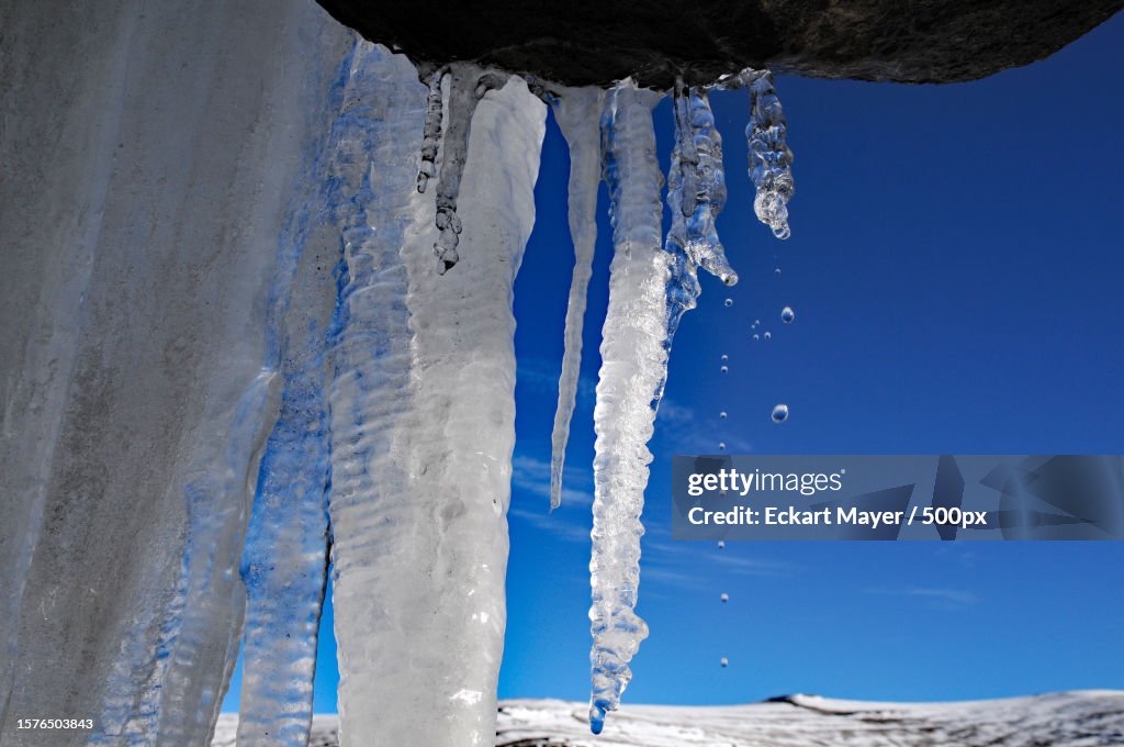 Low angle view of icicles on rock formation against sky