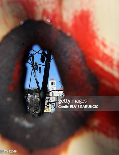 The Marijin Dvor square in Sarajevo is seen through a 20 year old shrapnel hole in a building currently under renovation on April 2, 2012. Sarajevo's...