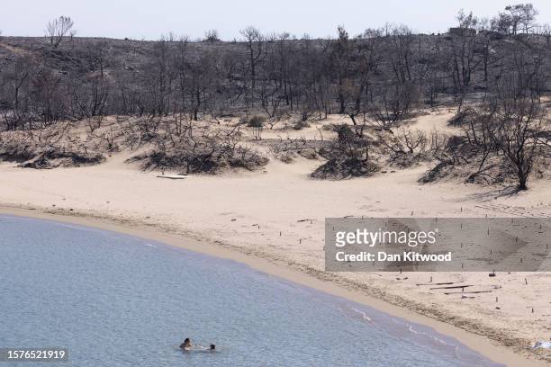 People relax on Glistra beach on July 28, 2023 in Lardos, Rhodes, Greece. The popular beach was ravaged by wildfire that also destroyed the up-market...