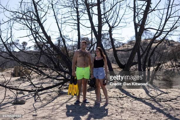 Nickolas Balgouranidis, and his wife Eleni Kottorou stand under the relative shade of a burnt tree on Glistra beach on July 28, 2023 in Lardos,...