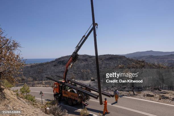 Workers restore power cables on July 28, 2023 in Vati, Rhodes, Greece. While firefighting planes and helicopters are still dealing with sporadic...