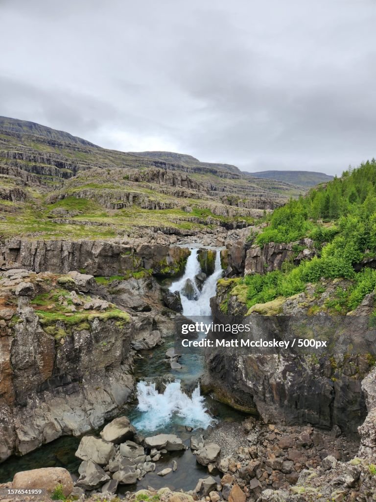 Scenic view of stream amidst rocks against sky