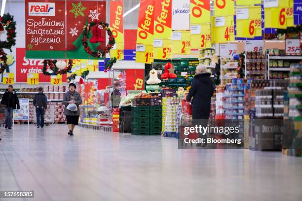 Customers browse goods beneath discounted product signs inside a Real supermarket in Wroclaw, Poland, on Wednesday, Dec. 5, 2012. Metro AG, Germany's...