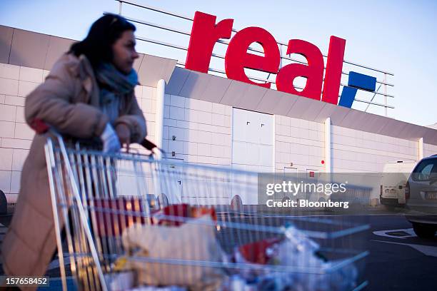 Customer pushes a shopping cart past a logo outside a Real supermarket in Wroclaw, Poland, on Wednesday, Dec. 5, 2012. Metro AG, Germany's biggest...
