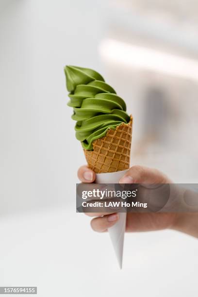 a hand holding a matcha ice-cream cone. - ice cream cone stockfoto's en -beelden