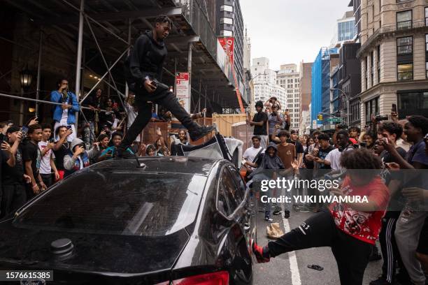 People jump on a car during riots sparked by Twitch streamer Kai Cenat, who announced a "givaway" event, in New York's Union Square on August 4,...