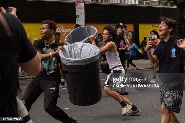 People throw trash bins at police officers during riots sparked by Twitch streamer Kai Cenat, who announced a "givaway" event, in New York's Union...