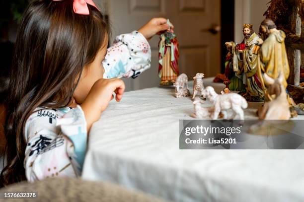 ragazza di razza mista gioca con il presepe vintage ambientato durante le vacanze a casa - natività foto e immagini stock