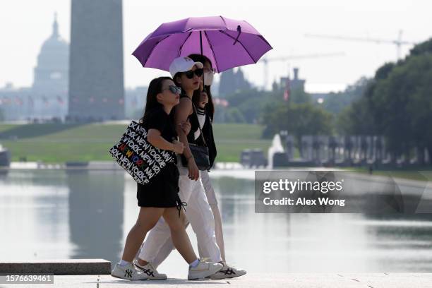 With the Washington Monument and the U.S. Capitol are seen in the background, tourists pass by the Lincoln Memorial Reflecting Pool on July 28, 2023...