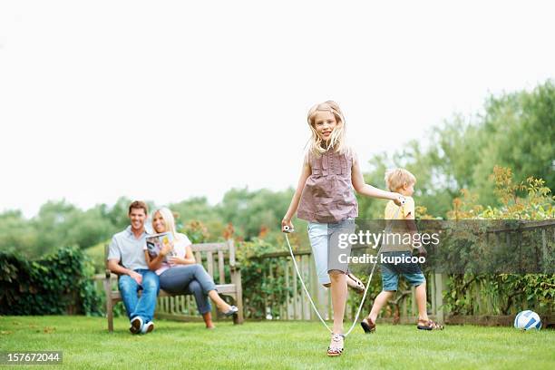 boy and girl enjoying while parents sitting on bench - skip stockfoto's en -beelden