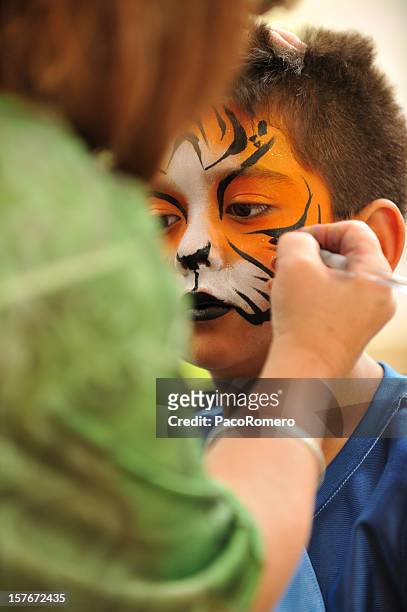 little  boy having a tiger mask painted on his hace - kinder schminken stockfoto's en -beelden