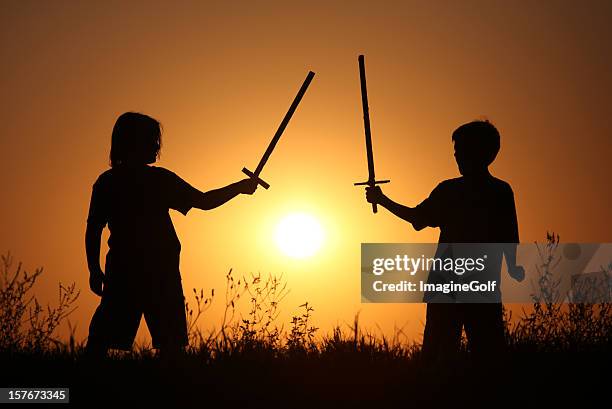 silhouette of two children with fantasy swords - sword fight stock pictures, royalty-free photos & images