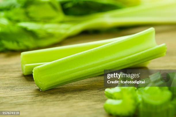 cut celery sticks and leaves on wooden table - bleekselderij stockfoto's en -beelden