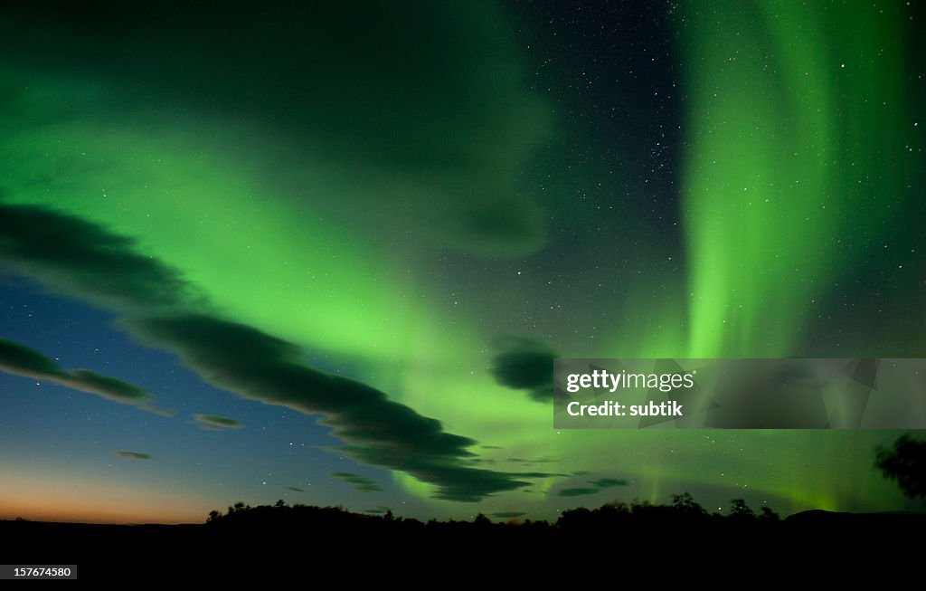 The aurora borealis paints the  night sky with green