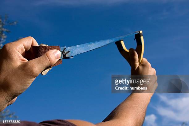 a rock is pulled back in an sling shot pointed to the sky - slingers stockfoto's en -beelden