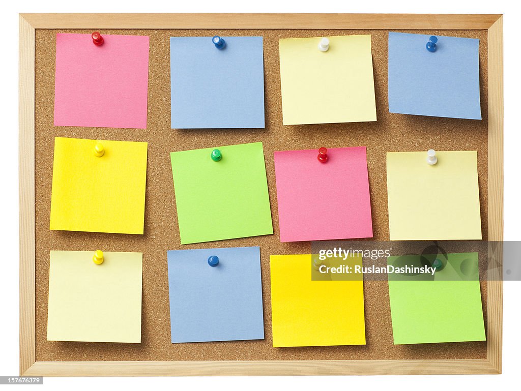 Office cork board full of colored memo notes.