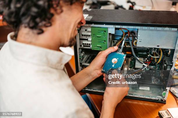 technicien installant un composant de disque dur dans un atelier - computer store photos et images de collection