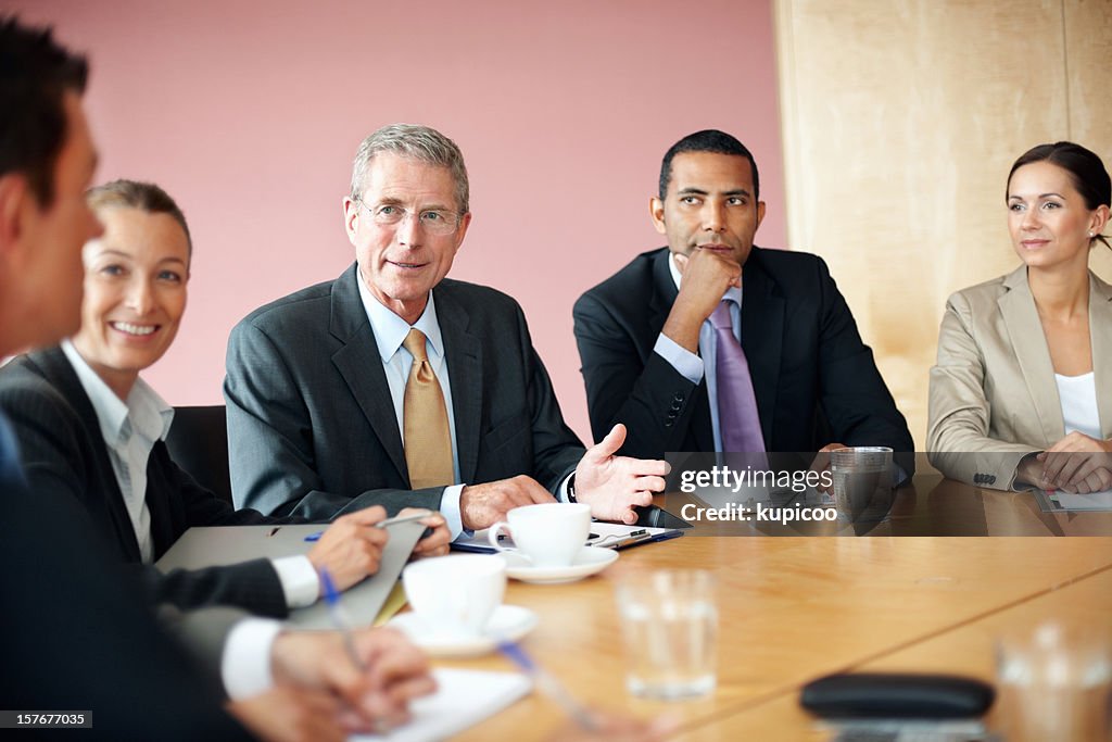 Mature business man discussing with his team in conference room