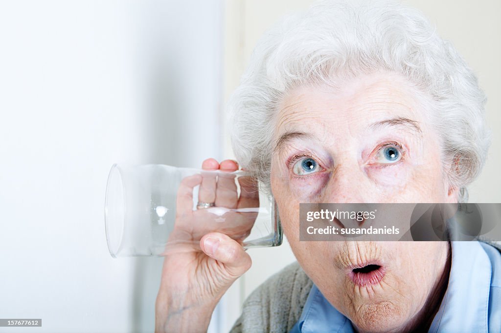 An old woman looking shocked with a glass on her ear