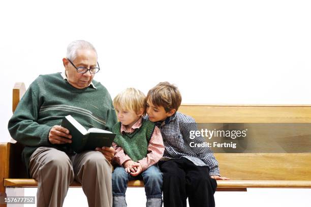 elderly man reading the bible to young children - family 2010 stock pictures, royalty-free photos & images