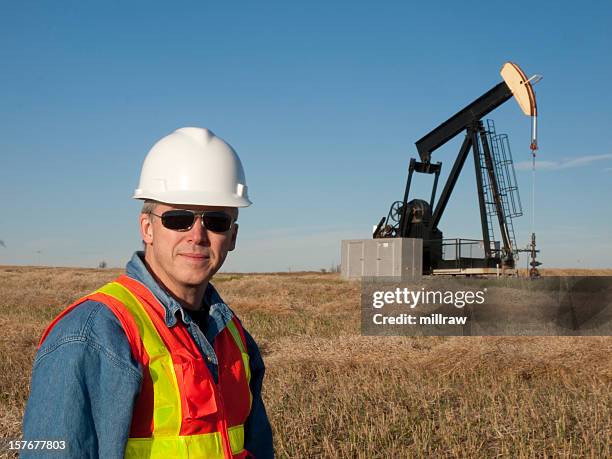 oil worker in safety gear at well pumpjack - oil worker stock pictures, royalty-free photos & images
