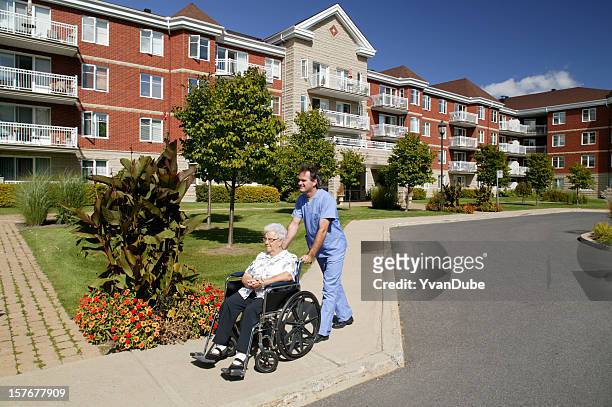 médico o al personal de enfermería impulsar una silla de ruedas al aire libre - residencia de ancianos fotografías e imágenes de stock