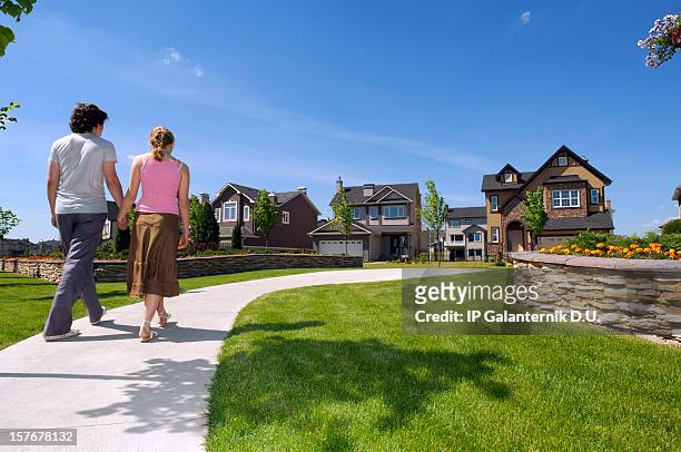 young couple walking in the suburbs towards a house - classic day 2 stockfoto's en -beelden