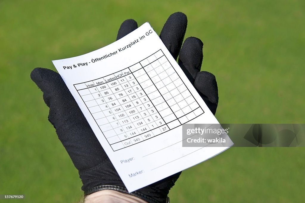 Balanced scorecard - holding golf card in hand with gloves