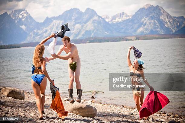 naked man getting his clothes stolen by two girls - skinny dipping girls stock pictures, royalty-free photos & images