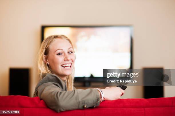 bellissimo biondo aspetto rotondo dalla televisione e sorrisi - home cinema foto e immagini stock