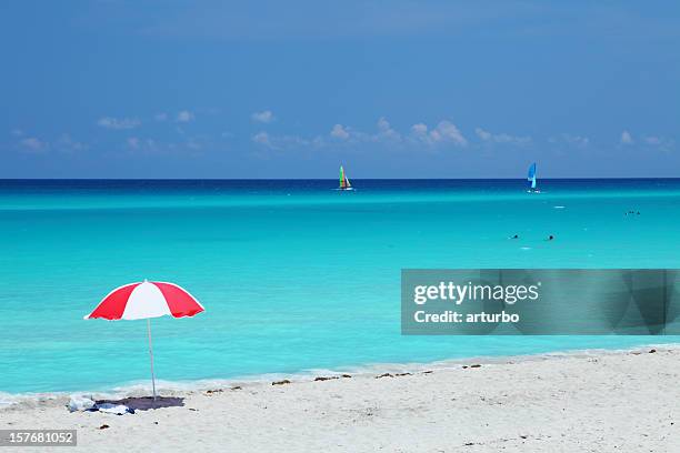 red and white umbrella against turquoise ocean - red hot cuba stock pictures, royalty-free photos & images