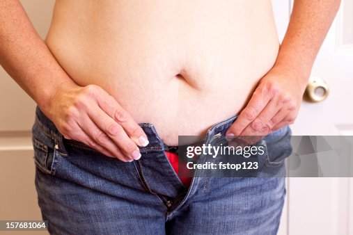 Overweight woman trying to button her jeans. Too tight. Belly. Overweight woman trying to button her jeans. Too tight. Belly.