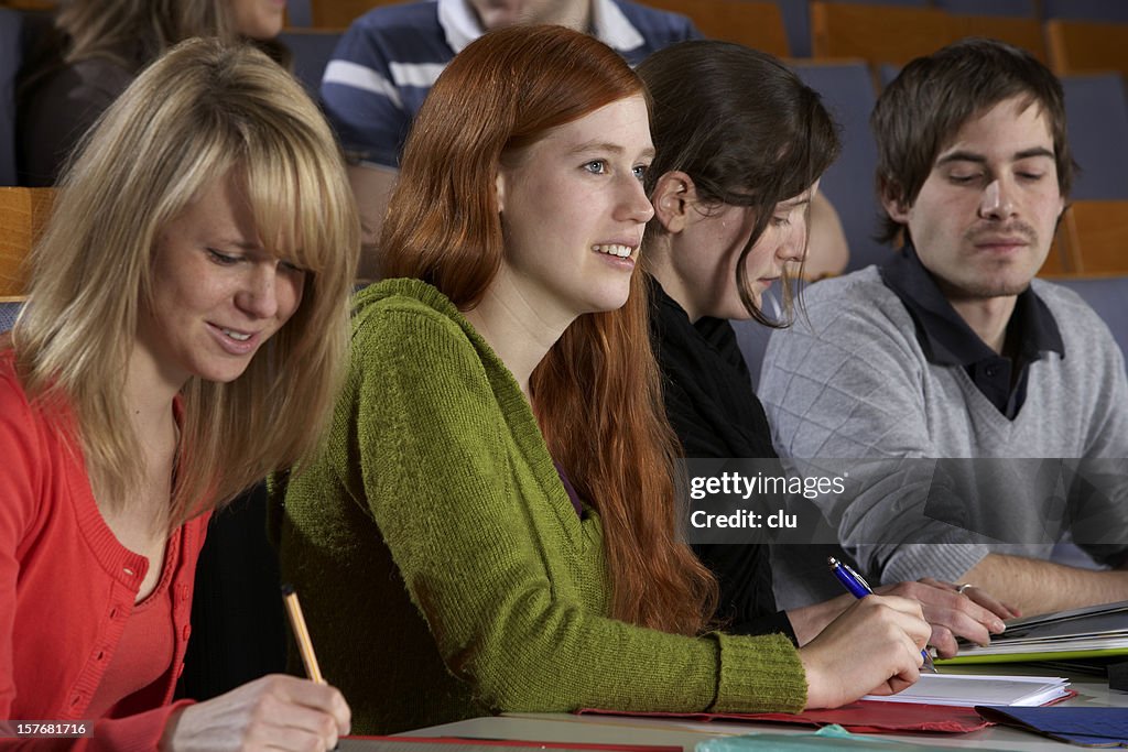 Young mixed students working and listening during lecture