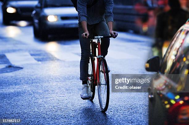 young adult on bike in the city, rainy evening traffic - pedestrian car stock pictures, royalty-free photos & images