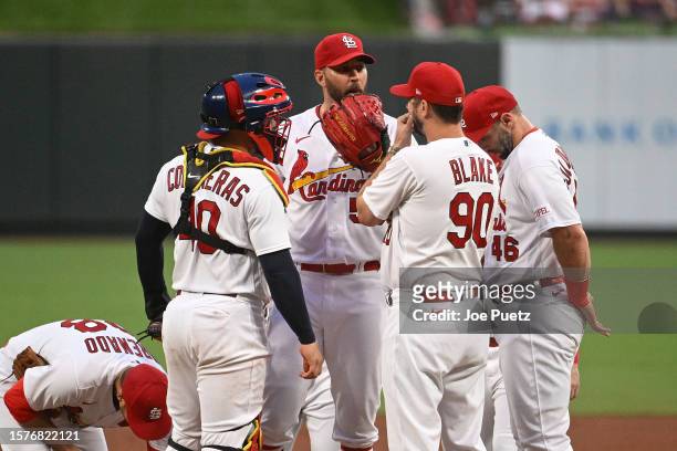 Pitching coach Dusty Blake of the St. Louis Cardinals speaks with Adam Wainwright and Willson Contreras in the second inning against the Colorado...