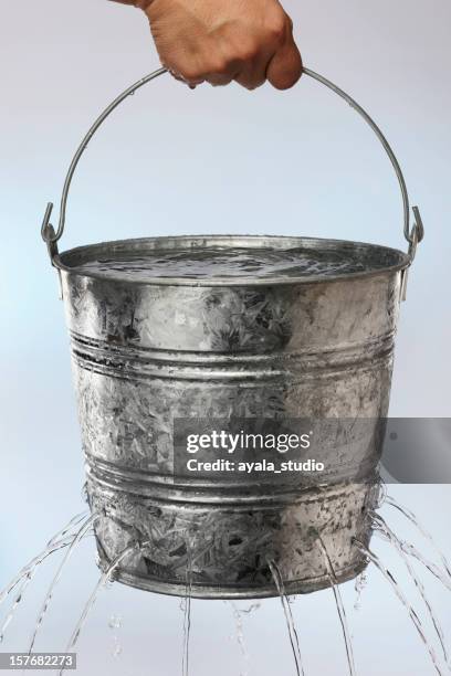 hand holding a bucket with holes leaking water - bucket stock pictures, royalty-free photos & images