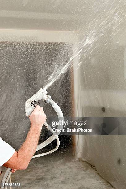 worker spraying drywall mud on a ceiling for knockdown texture - plaster stockfoto's en -beelden