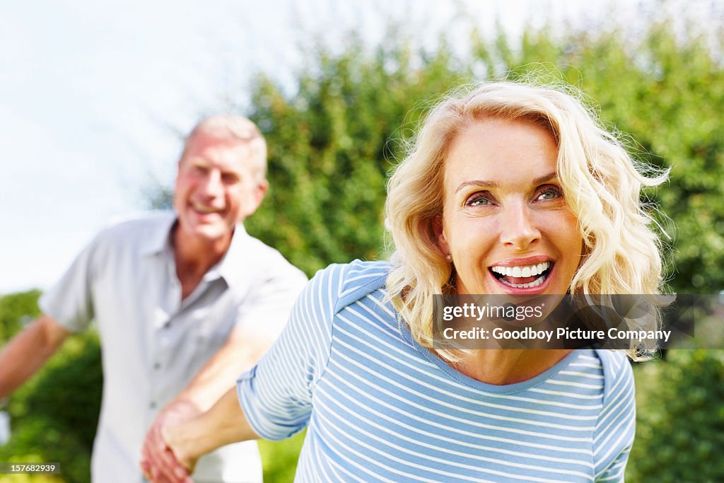 Fröhliche Frau hält hand eines älteren Mannes gegen Himmel