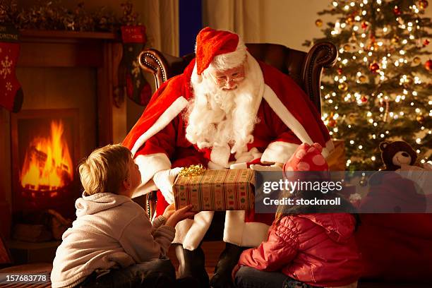 pai oferecendo de presente de natal para crianças em gruta - pai natal imagens e fotografias de stock