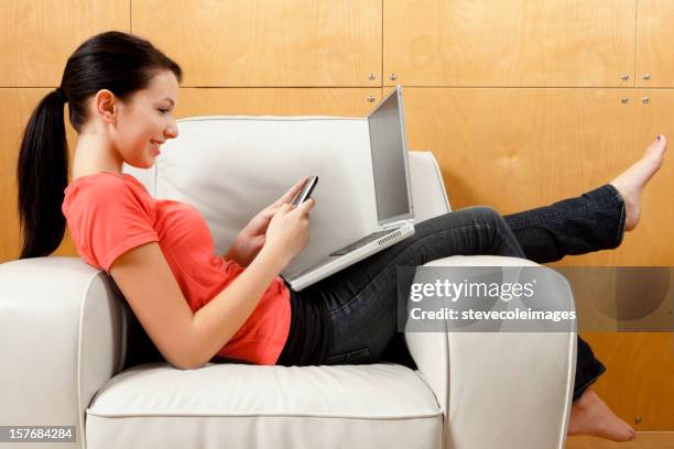 teenager with a laptop texting on the phone - girls barefoot in jeans stockfoto's en -beelden