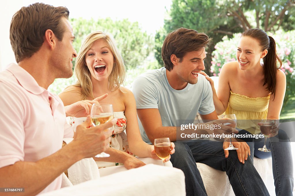 Group Of Young Friends Relaxing On Sofa Drinking Wine Together