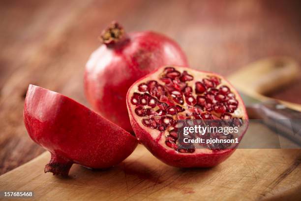 pomegranate fruit on cut board - granaatappel stockfoto's en -beelden