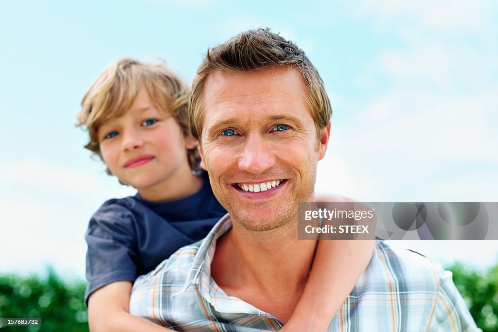 Smiling mature man piggybacking his son