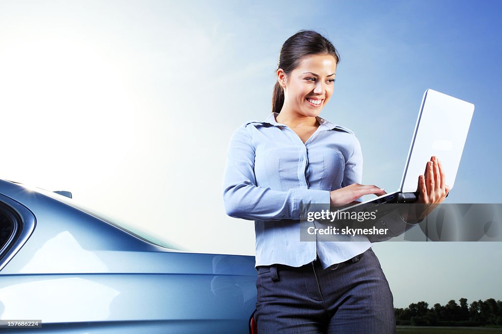 Beautiful woman outdoor typing on laptop computer.