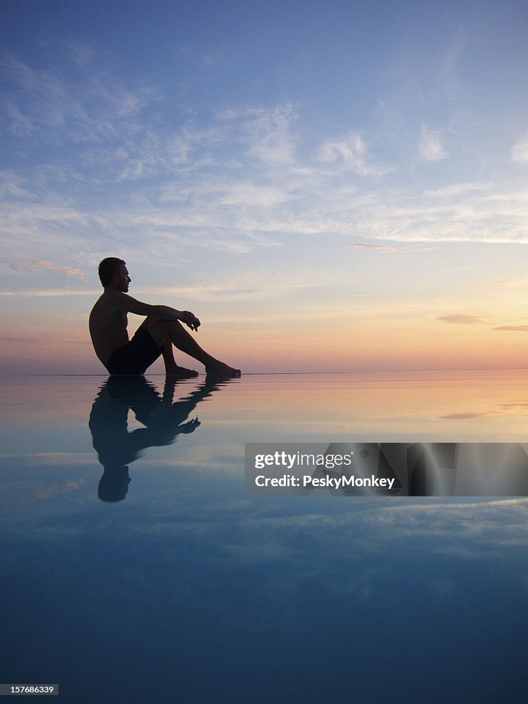 Silhouette eines Mannes, spiegelt sich in den Infinity-Pool bei Sonnenuntergang