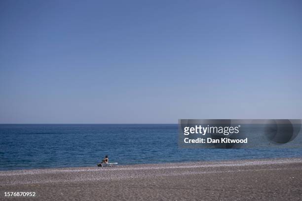 Lone sunbather on the beach on July 28, 2023 in Gennadi, Rhodes, Greece. While firefighting planes and helicopters are still dealing with sporadic...