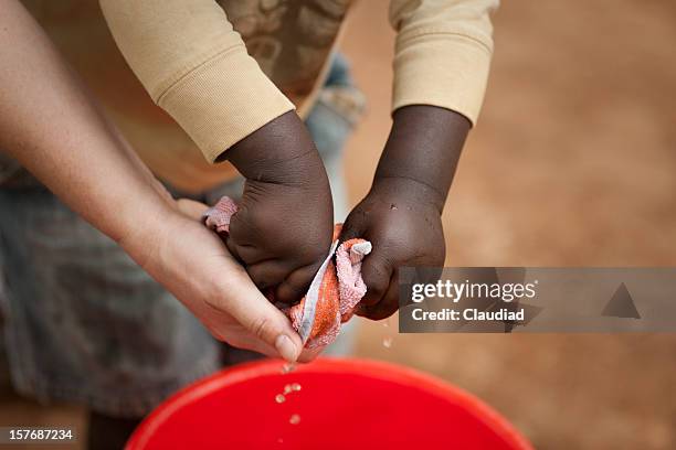 adult is helping african child with washing cloth - kenya children stock pictures, royalty-free photos & images