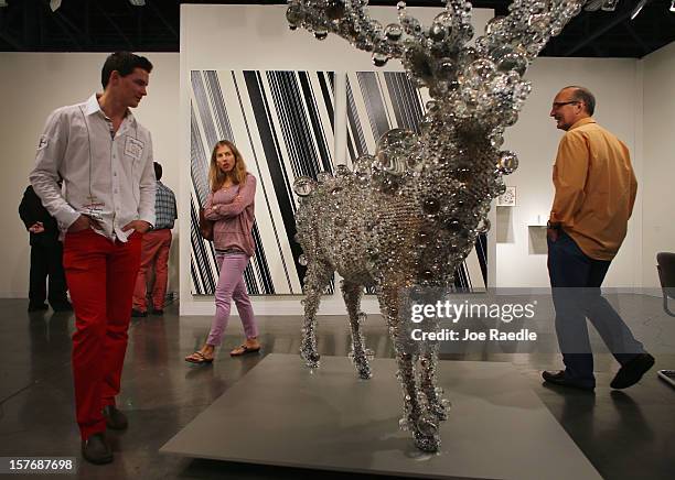 People look at a piece of art in the Scai The Bathhouse gallery as Art Basel opens at the Miami Beach Convention Center on December 5, 2012 in Miami...